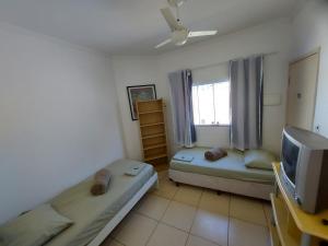 ein kleines Zimmer mit zwei Betten und einem Fernseher in der Unterkunft Quartos com Banheiros privativos - Hospedagem Recanto do Luar in Taubaté