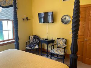 a bedroom with two chairs and a tv on the wall at The Inn at Woodsong Acres in Conneaut