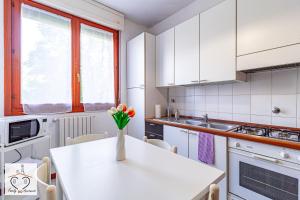 a kitchen with a white table with a vase of flowers on it at FamilyBO Apartments Sant'Orsola in Bologna