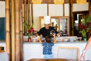 La Selva Eco-Lodge & Retreat في Providencia: رجل يرتدي قبعة شيفات يقف وراء فتاة صغيرة
