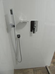 una ducha con una manguera pegada a una pared blanca en Meraki Host, en Cali