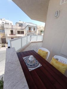 a balcony with a wooden table and chairs on a roof at "Joseph 2" Stylish corner flat with open views, just 5km from the beach in Siġġiewi