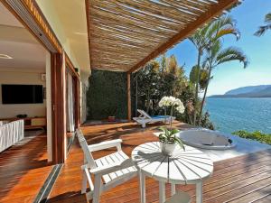 een houten terras met een tafel en stoelen en de oceaan bij Barra do Piuva Porto Hotel in Ilhabela