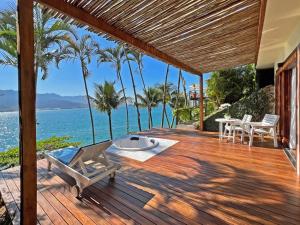 a wooden deck with a table and chairs and the ocean at Barra do Piuva Porto Hotel in Ilhabela