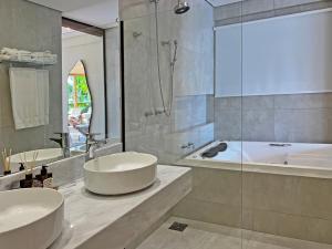 a bathroom with a tub and a sink and a bath tub at Barra do Piuva Porto Hotel in Ilhabela