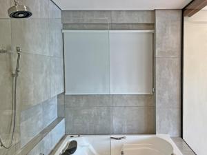 a bathroom with a bath tub and a shower at Barra do Piuva Porto Hotel in Ilhabela