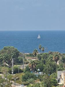 a sail boat in the ocean with a ship in the distance at Apartment in Akko with Sea View in ‘Akko