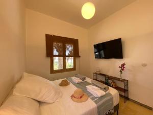 een slaapkamer met een bed met witte lakens en een televisie bij La Casita a 60 pasos del mar in Tamaduste