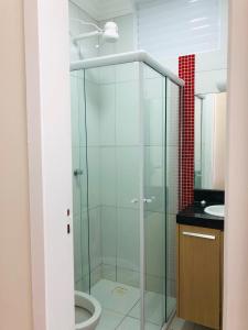 uma casa de banho com uma cabina de duche em vidro, um WC e um lavatório. em Chemin Suites em Balneário Camboriú