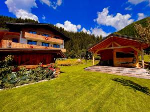 a house with a porch next to a grass yard at Montanara Apartment & Zimmer in Ramsau am Dachstein