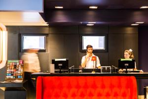 a man standing in front of a counter with a microphone at Ibis Styles Porto Alegre Centro in Porto Alegre