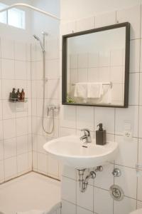 Baño blanco con lavabo y espejo en Stadtoase Wohnung nahe Hauptbahnhof, en Coblenza
