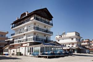 a large white building with chairs in front of it at Nepheli in Paralia Katerinis