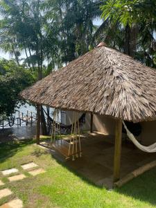 a straw hut with a hammock and a straw roof at Pousada Casa Dunas in Barreirinhas