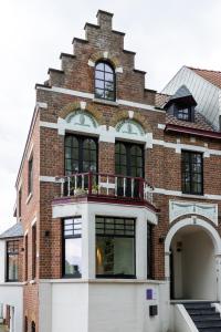 a brick building with a balcony on top of it at Doux Foyer in De Haan