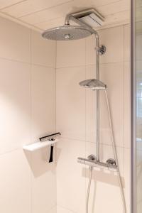 a shower in a bathroom with a shower head at Doux Foyer in De Haan