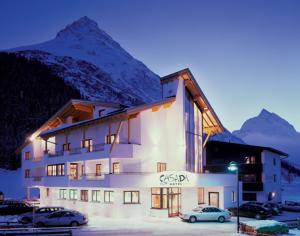a building with cars parked in front of it with a mountain at Ferienwohnung CASADA im Hotel Casada in Galtür