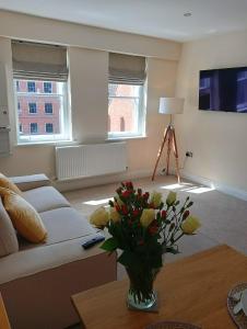 una sala de estar con sofá y un jarrón de flores en Barchester House Apartment Standard en Salisbury