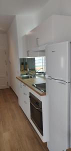 a kitchen with white cabinets and a white refrigerator at Estudio Paradise View - Playa Paraíso Tenerife in Adeje