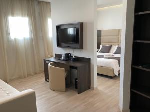 Habitación con escritorio, TV y cama. en HotelLuxuryPrato, en Prato