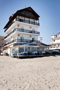 un edificio en la playa con sillas y sombrillas en Nepheli, en Paralia Katerinis