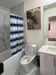 a bathroom with a toilet and a sink and a shower curtain at Modern Suite by Spruce Meadows in Calgary
