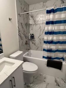 a bathroom with a toilet and a shower curtain at Modern Suite by Spruce Meadows in Calgary