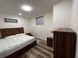 a bedroom with a bed with a wooden headboard at Modern Suite by Spruce Meadows in Calgary
