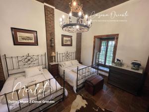 a bedroom with two beds and a chandelier at Hotel Boutique Casona Oriente in De Cauquenes