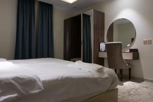 1 dormitorio con cama, espejo y silla en أزهار النرجس للشقق الفندقية, en Umm al Khashab