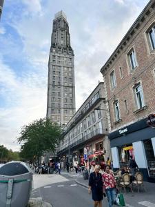 two people walking down a street with a tall building at Appt 2 à deux pas de la gare d'Amiens in Amiens