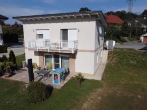 a white house with a balcony and a yard at Ferienhaus Sole in Velden am Wörthersee