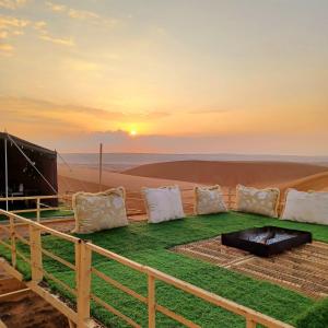 ein Feld mit Kissen und einem Grill in der Wüste in der Unterkunft Sunrise Desert Local Private Camp in Badīyah
