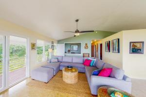 ein Wohnzimmer mit einem blauen Sofa und rosa Kissen in der Unterkunft Hale Kai in Keaau