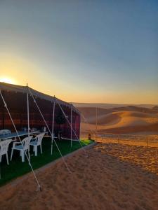 Sunrise Desert Local Private Camp في Badīyah: خيمة مع طاولات وكراسي في الصحراء