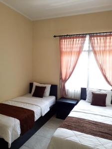 - 2 lits dans une chambre avec fenêtre dans l'établissement Unram Guest House, à Tjakranegara
