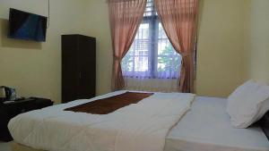 - une chambre avec un grand lit blanc et une fenêtre dans l'établissement Unram Guest House, à Tjakranegara