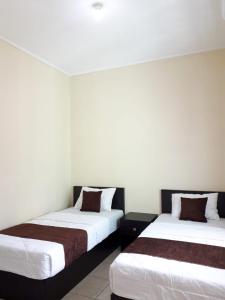 - deux lits assis l'un à côté de l'autre dans une pièce dans l'établissement Unram Guest House, à Tjakranegara