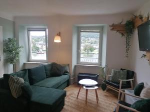 a living room with a couch and a table and two windows at Voll ausgestattete Wohnung mit Moselblick in Alf