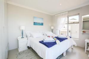 a white bedroom with a bed with towels on it at Imberbe in Struisbaai