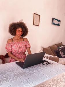 Eine Frau, die an einem Tisch mit einem Laptop steht. in der Unterkunft Casa em arraial do cabo / Monte Alto in Arraial do Cabo