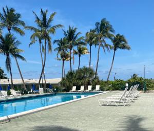 a swimming pool with lounge chairs and palm trees at Silver Sands Beach Resort in Miami