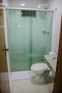 uma casa de banho com um WC e uma cabina de duche em vidro. em Domus Hotel Palmeiras Canaã dos Carajás em Canaã dos Carajás