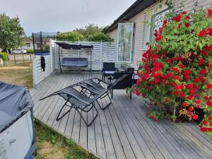 a wooden deck with a table and chairs and red flowers at KLİPPSTİGEN in Hultsfred