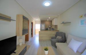 Apartamento Arenales del sol في آريناليس ديل سول: غرفة معيشة مع أريكة وتلفزيون ومطبخ