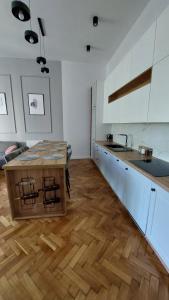 a kitchen with white cabinets and a wooden table at Bonjour Apartment bezpłatny parking in Łódź