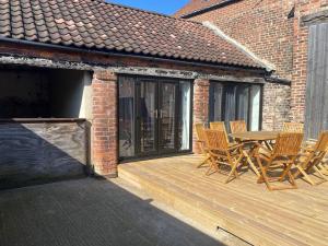 une terrasse en bois avec une table et des chaises. dans l'établissement Spacious 4 bedroom, 4 bathroom barn conversion home with private garden and free parking, à Burn