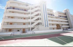 a large building with a tennis court in front of it at Apartamento Arenales del sol in Arenales del Sol