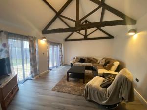 a living room with two couches and a tv at Spacious 4 bedroom, 4 bathroom barn conversion home with private garden and free parking in Burn
