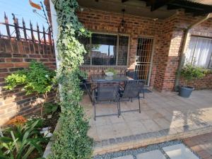 un patio con mesa y sillas en una pared de ladrillo en The Retreat Guesthouse en Kimberley